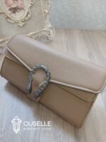 شنطة كتف نسائية جلد باللون الكافي بمقبض سلسلة فضية داكنة وقفل معدني مزخرف.