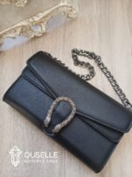 شنطة كتف نسائية جلد باللون الأسود بقفل معدني مزخرف وسلسلة فضية داكنة.